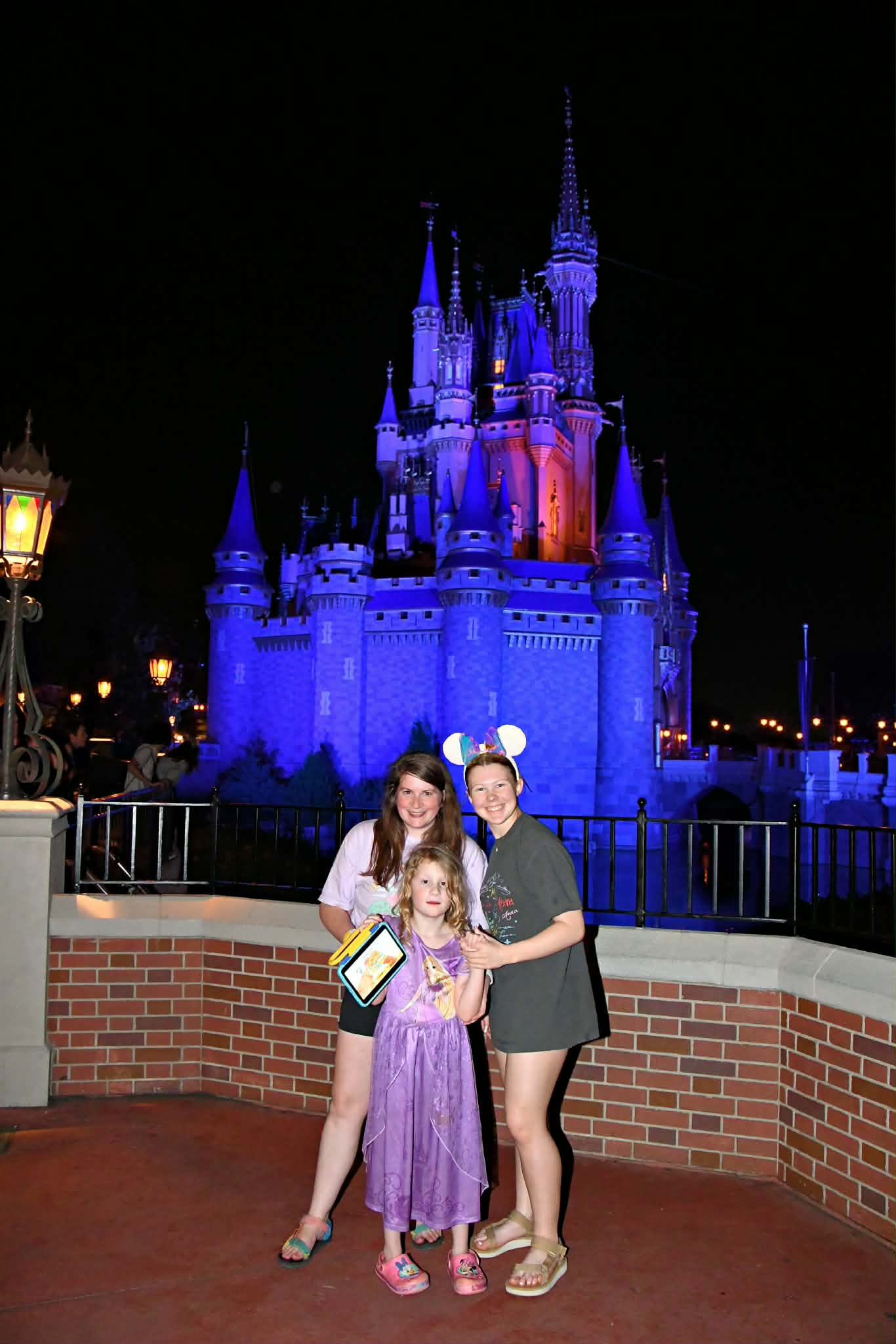 Mom and daughter in front of Cinderella Castle lit up at night